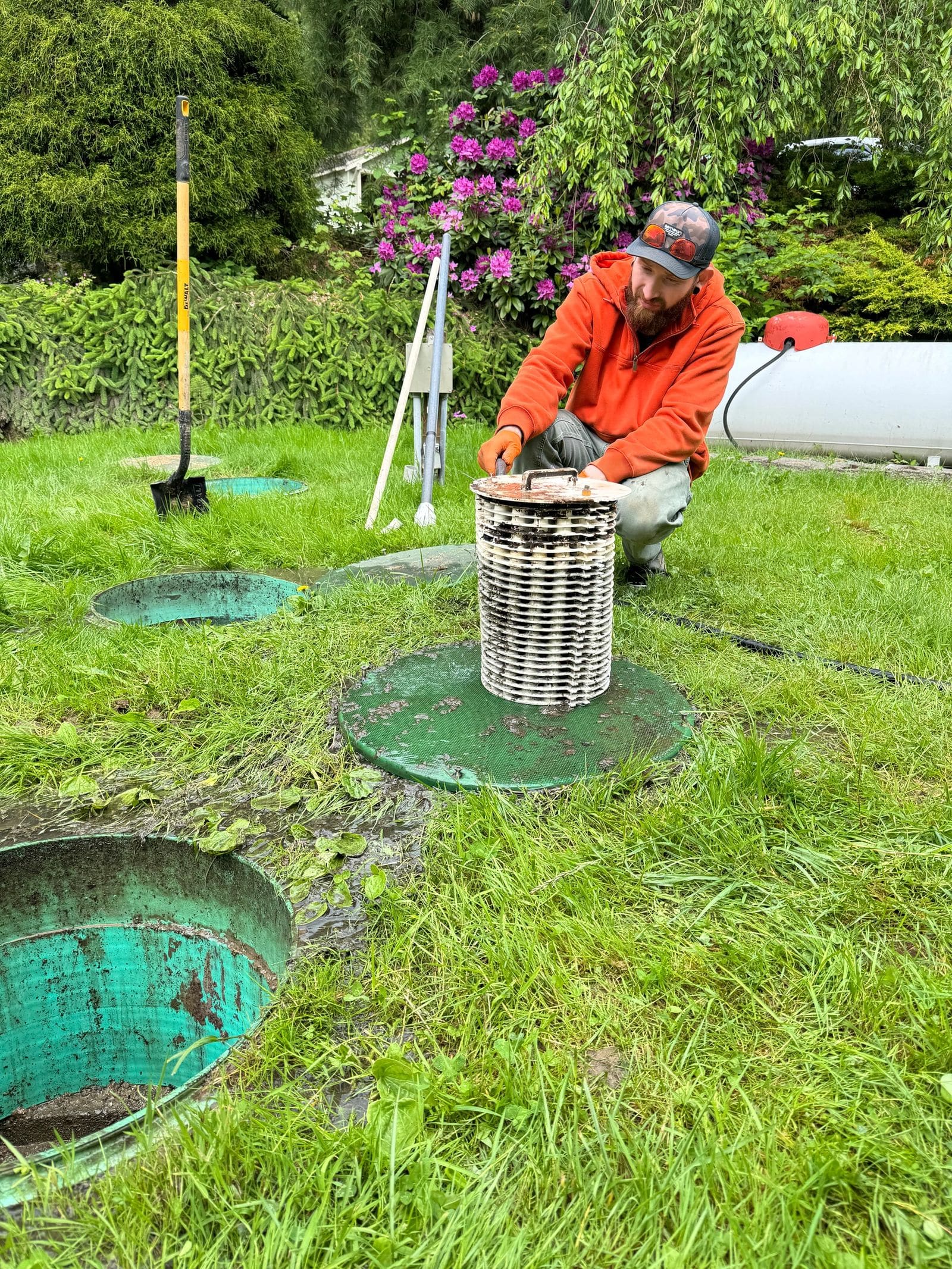 A Tiger Tank Pumping technician servicing a septic outlet filter at an open riser.