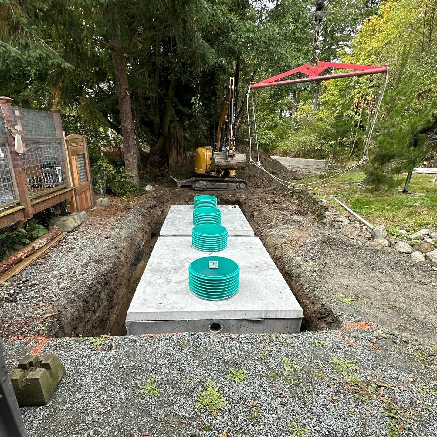 New concrete septic tanks with green risers being set by crane.