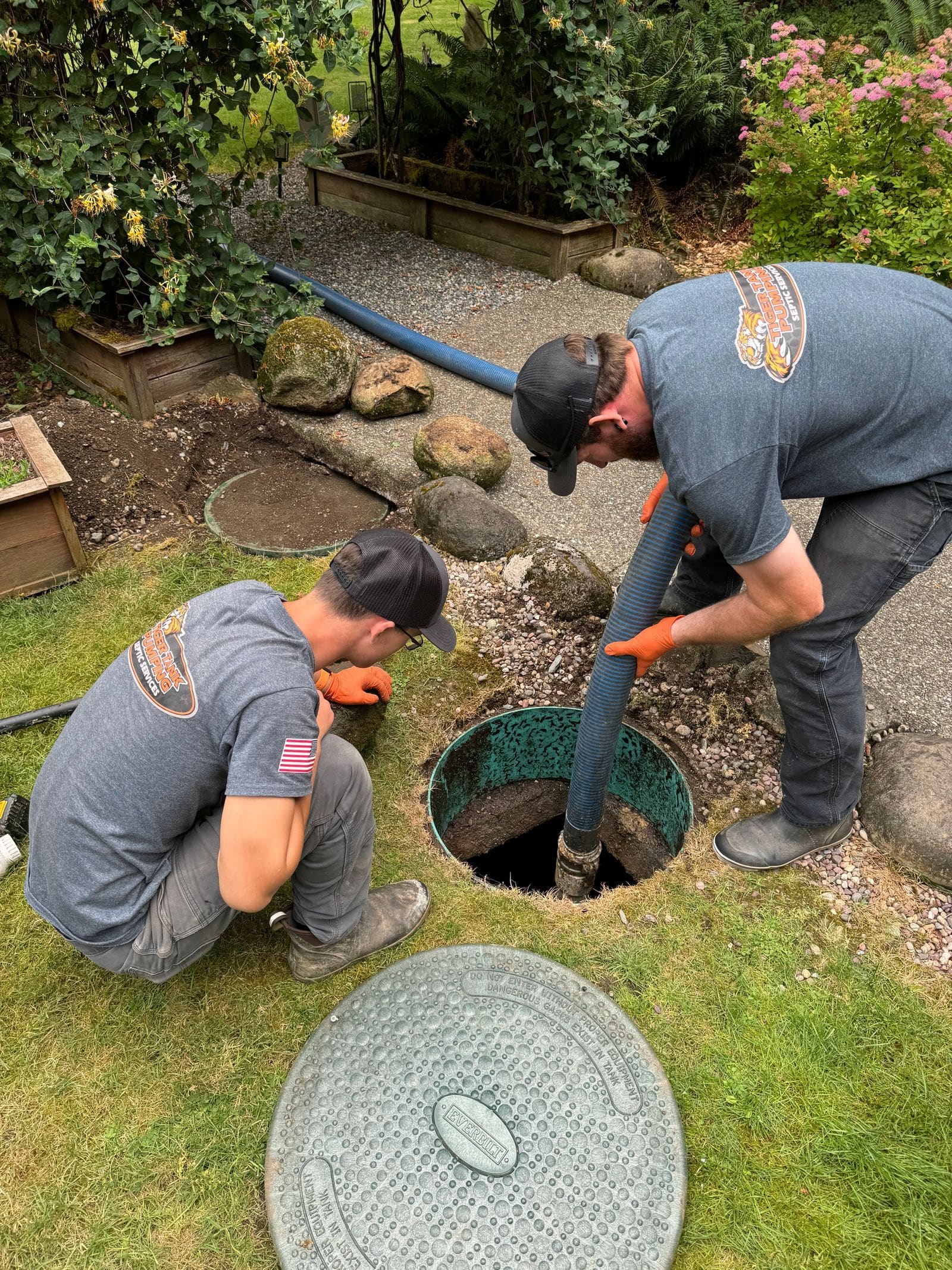 Two Tiger Tank Pumping technicians pumping a septic tank through an open riser.